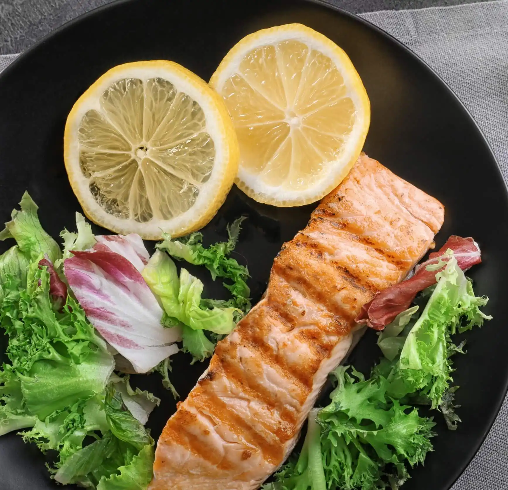 salmon with leafy greens and lemon slices